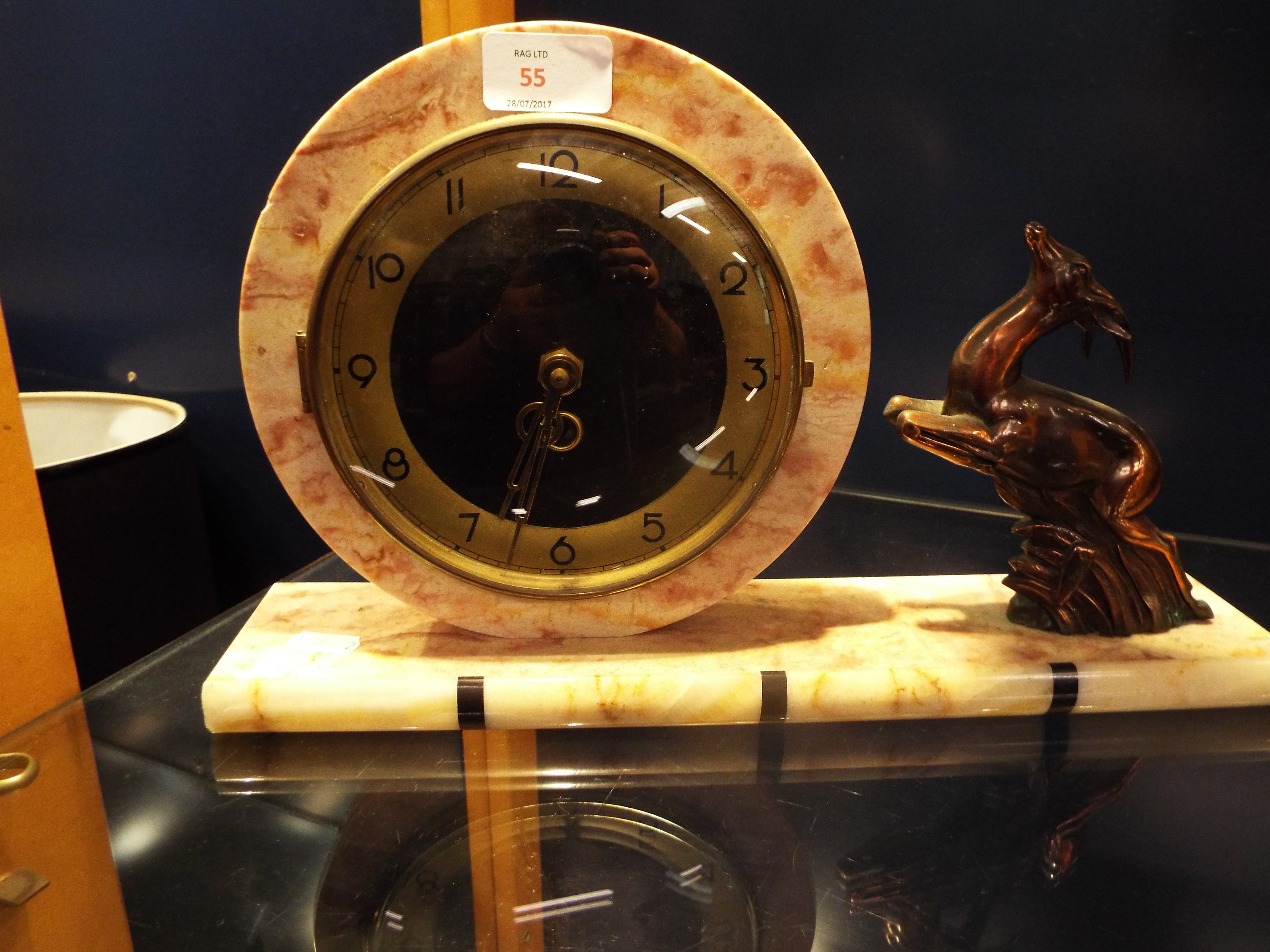 An Art Deco circular marble mantel clock on rectangular base flanked by a leaping deer