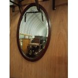 A mahogany satin wood strung bevelled glass oval mirror