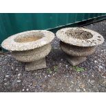 A pair of reconstituted stone pedestal garden urns