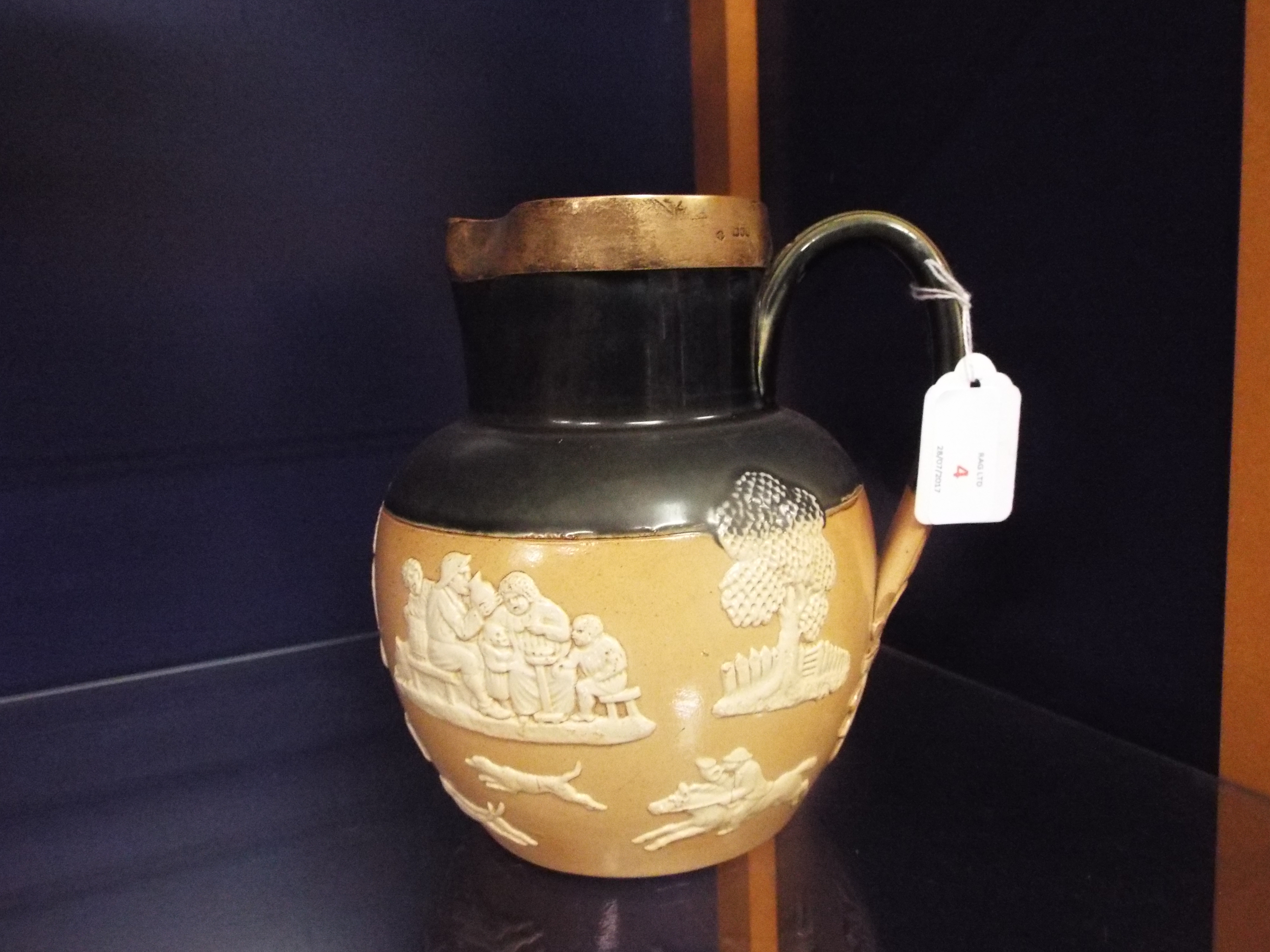 An Edwardian black glazed Doulton Lambeth harvest jug with silver rim,