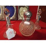 Two silver collared faceted glass scent bottles together with a silver lidded scent bottle,