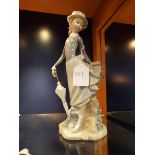 A Lladro figurine of a young lady with parasol resting against a stump,