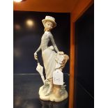 A Lladro figurine of a young lady with parasol resting against a stump,