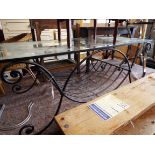 A black painted wrought iron coffee table of scrolling form with glass top