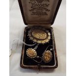 A white metal brooch and earring set with applied gold floral design