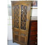 Oak corner cupboard with two upper glazed doors above two carved and panelled doors