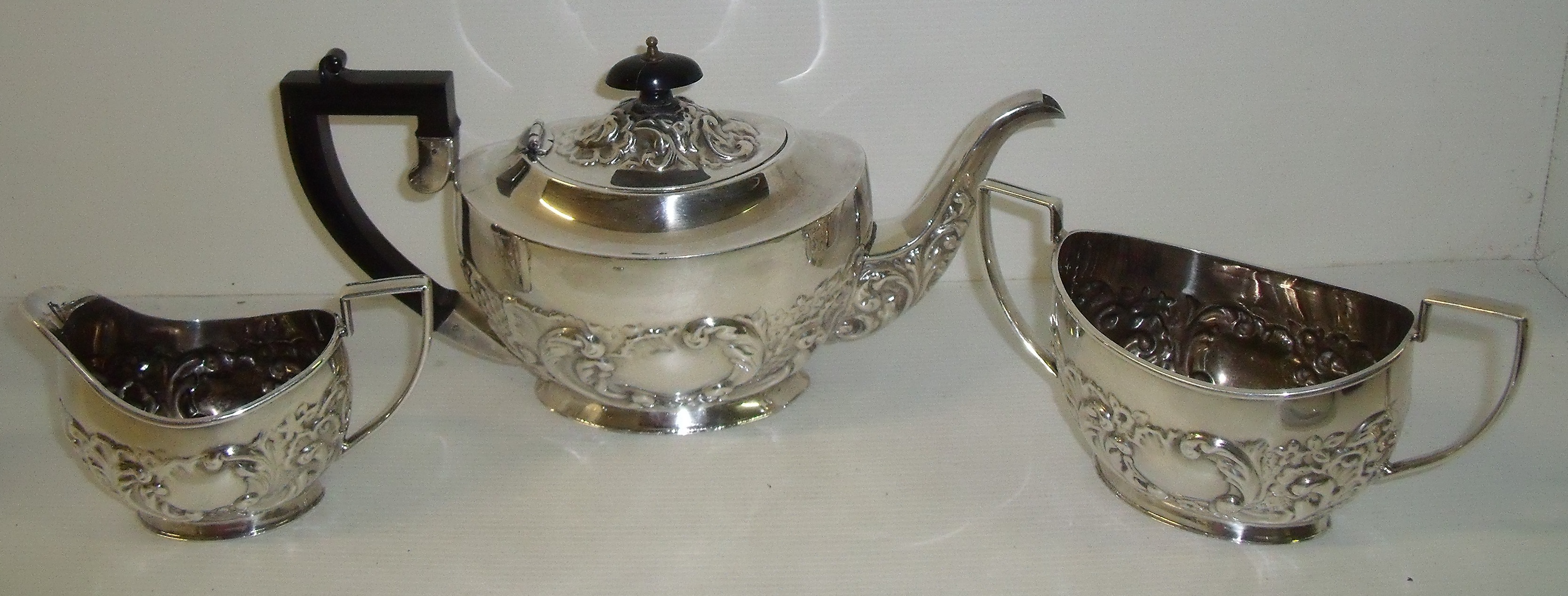 Three piece silver plated tea set with repousse floral pattern