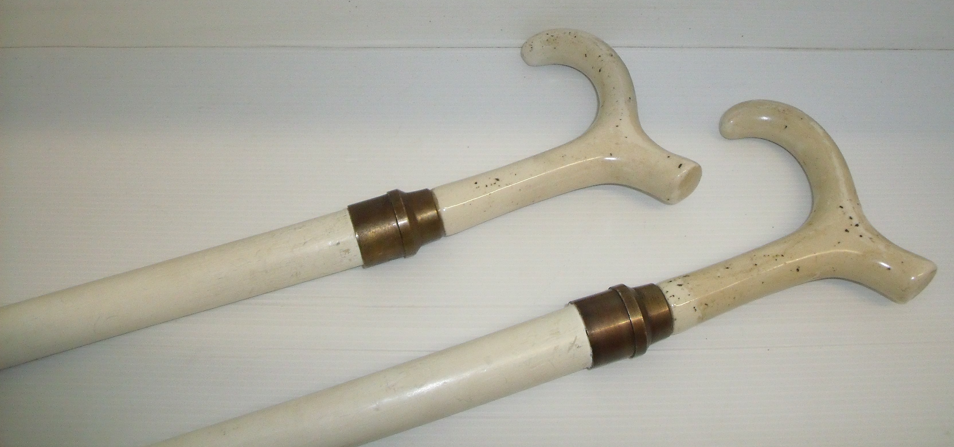 Pair of white painted walking sticks with ceramic thumb stick style handles