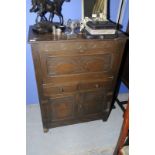 Oak side cabinet with carved detail and fall front above two drawers and two cupboard doors