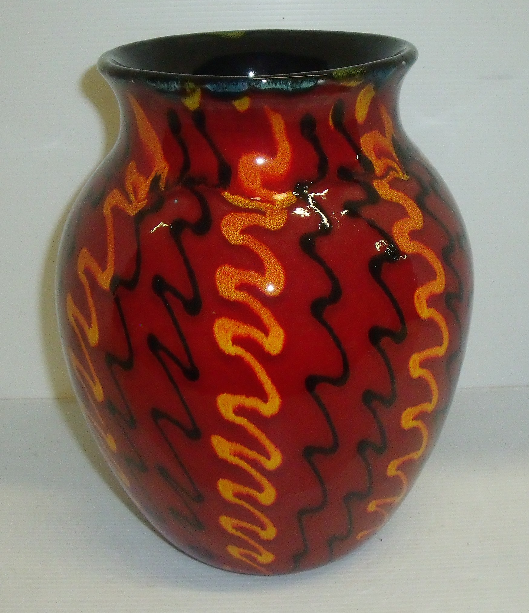 Poole Pottery vase in red glaze with squiggle patterns covering the body