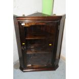 Stained pine wall hanging corner cupboard enclosed by single glazed door