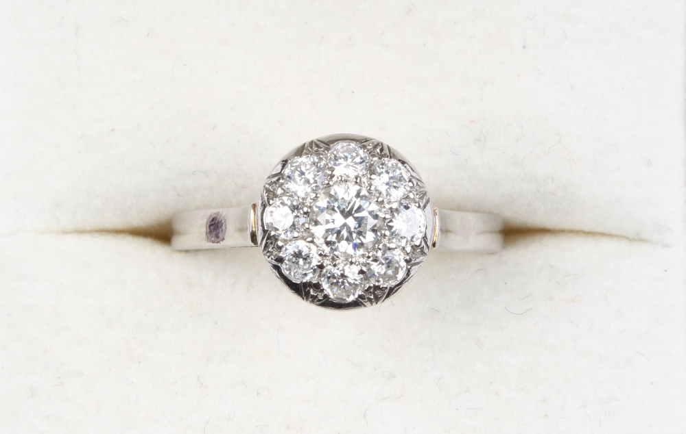 A French platinum diamond cluster ring, the central brilliant cut stone approximately 0.2 carat, the