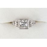 A Continental diamond ring, the central brilliant cut diamond in raised square setting, the