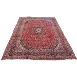 A Meshed woollen hand-made carpet with red ground, 150 by 114ins. (380 by 290cms.) (see
