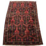 A Belouch woollen hand-made rug with dark red ground, 115 by 55ins. (294 by 140cms.) (see