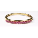 A fine yellow gold hinged bracelet set with fifteen unheated oval cut Thai rubies, the estimated
