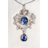 A fine sapphire & diamond pendant, the ribbon crested foliate openwork frame with two suspended