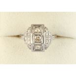 A French Art Deco platinum diamond ring, with a row of three diamonds in angled millegrain