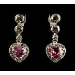 A pair of white gold pink sapphire & diamond pendant earrings, each with a heart shaped cut pink