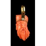 A yellow gold mounted carved pink coral pendant modelled as the head of a sage, set with a single