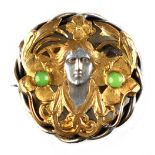 An Art Nouveau style white metal & gilt brooch modelled as the head of a maiden set with cabochon