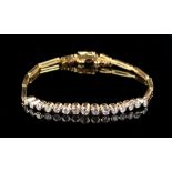 An unmarked yellow gold diamond bracelet, with fifteen collet set diamonds flanked by two-bar links,