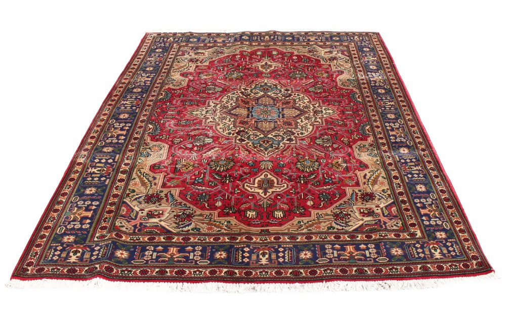 A Tabriz woollen hand-made carpet with dark red ground, 122 by 82ins. (310 by 207cms.) (see