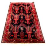 A Belouch woollen hand-made rug with red ground, 95 by 49ins. (242 by 124cms.) (see illustration).