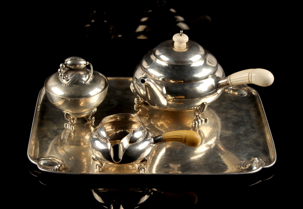 A Georg Jensen ‘Blossom’ pattern silver three piece tea set on tray, designed in 1918, with turned