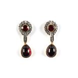 A pair of Continental yellow gold garnet & diamond pendant earrings, each with a cabochon pear