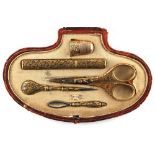 A late 19th / early 20th century Spanish red leather cased gilt metal sewing set with associated