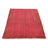 A Turkoman woollen hand-made rug with red ground, 74 by 52ins. (187 by 132cms.) (see illustration).