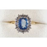 An 18ct yellow gold sapphire & diamond cluster ring, the pale oval cut sapphire weighing