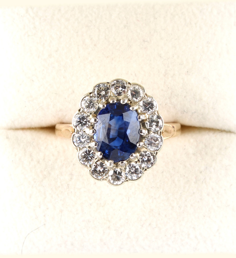 A good yellow gold sapphire & diamond cluster ring, the vivid blue oval cut sapphire weighing