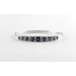 A sapphire & diamond hinged bracelet, the nine graduated oval cut sapphires weighing approximately 3