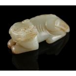 A Chinese carved very pale celadon & russet jade model of a recumbent temple lion, 2.85ins. (7.