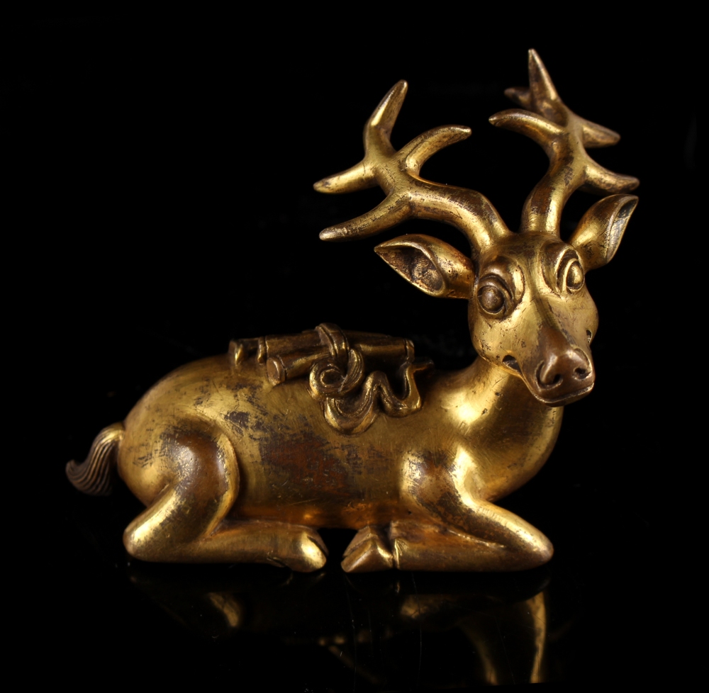 A Chinese gilt bronze scroll weight modelled as a recumbent deer, 2.55ins. (6.5cms.) high (see