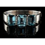 A good French white gold hinged bracelet set with three large aquamarines bordered by rows of