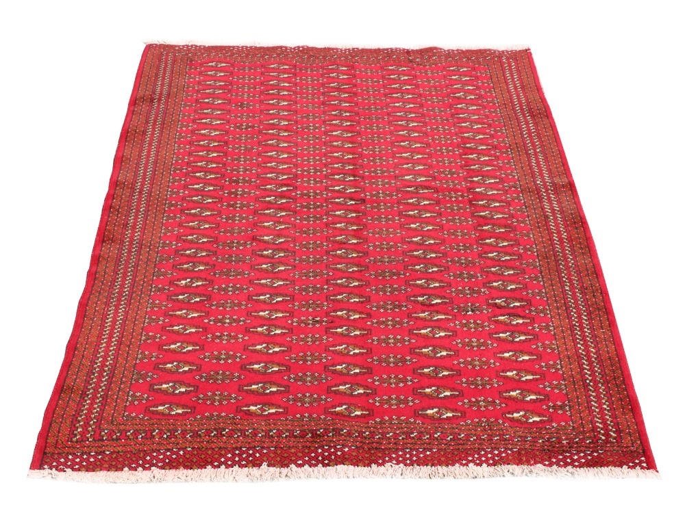 A Turkoman woollen hand-made rug with red ground, 74 by 52ins. (187 by 132cms.) (see illustration).