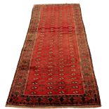 A Turkoman woollen hand-made long rug with red ground, 122 by 53ins. (309 by 134cms.) (see