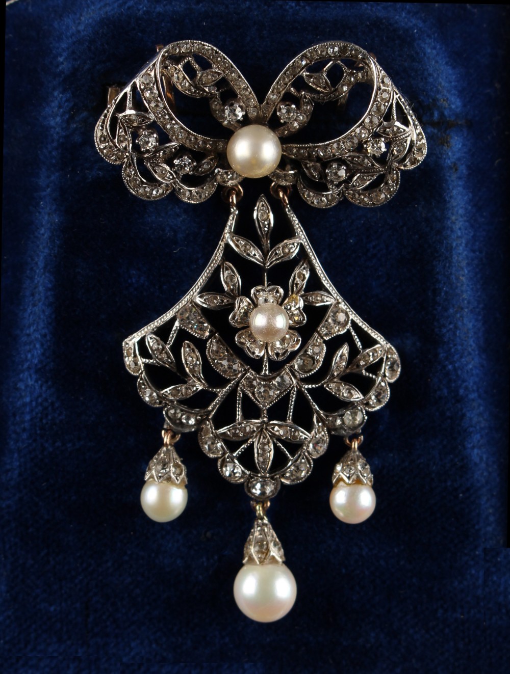 A late 19th century pearl & paste ribbon & foliate pendant brooch, indistinctly marked to