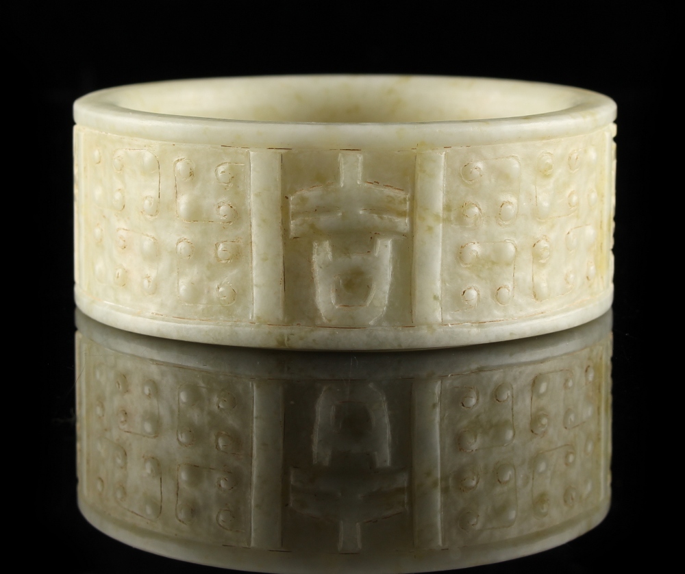 Property of a gentleman - a Chinese archaistic carved pale celadon hardstone bangle, 3.25ins. (8.