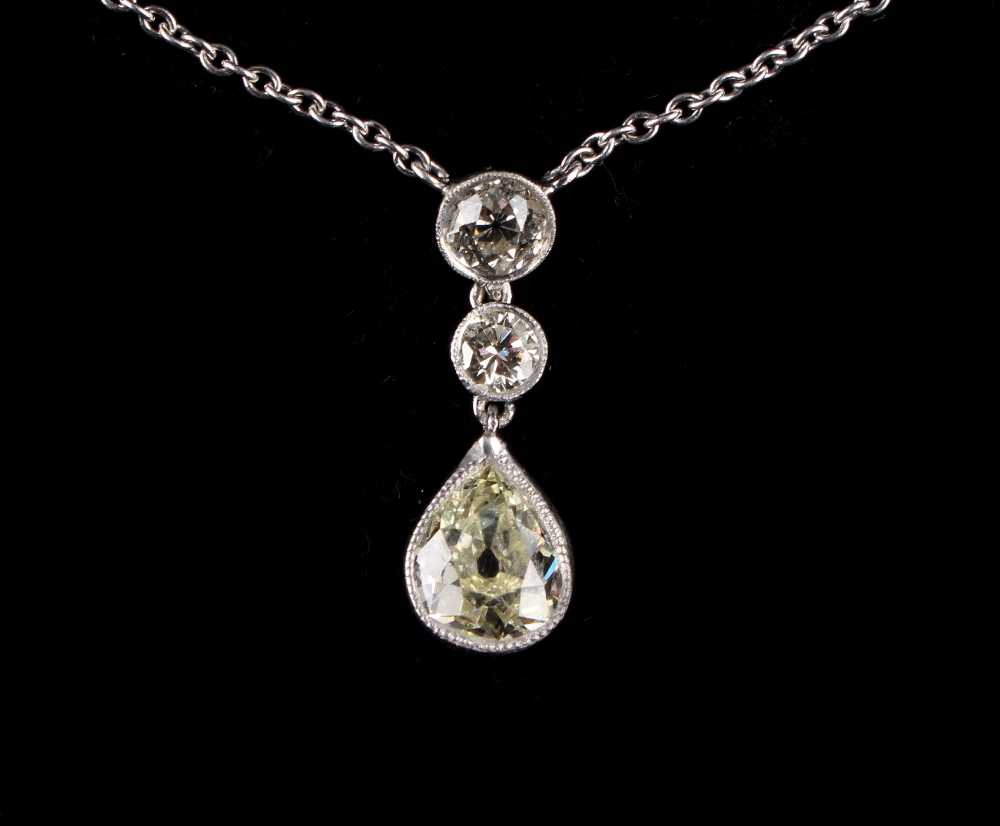 A platinum diamond three-stone pendant necklace, the largest pear shaped diamond weighing