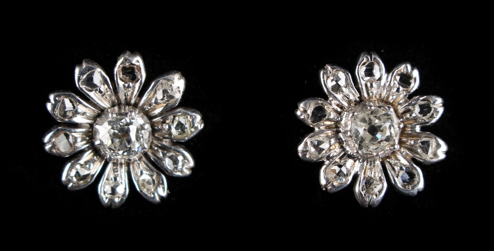 A pair of unmarked white gold diamond flowerhead earrings, each with a central diamond within ten