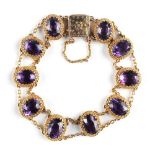 An unmarked Victorian yellow gold oval cut amethyst bracelet, with engraved box clasp & safety chain