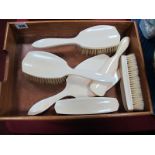 An Early XX Century Ivory Backed Dressing Table Set, comprising a hand mirror, two hair brushes, a