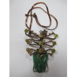 A Large Abstract Pendant, of stylised mask design below scroll mount with applied bead detail,