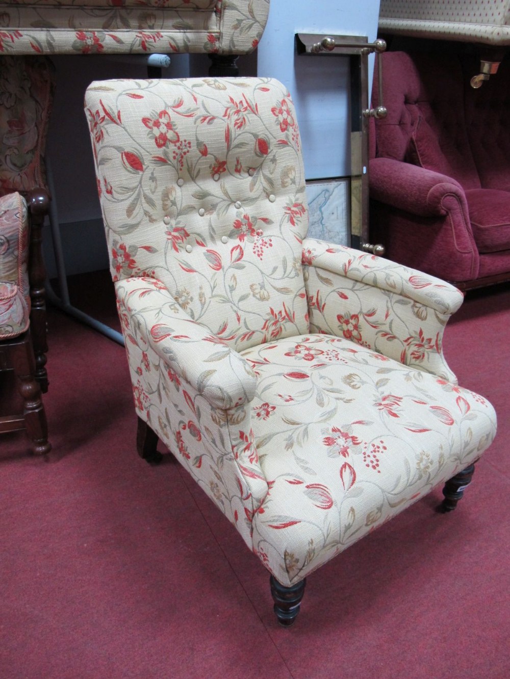 Early XX Century Armchair, upholstered in a floral fabric, on turned legs.