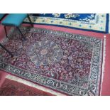 A Kashan Style Rug, the wine red field with central medallion bordered by scrolling plant forms, the