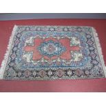 An Indian Rug in the Persian Manner, the salmon pink field with central shaped blue medallion, the